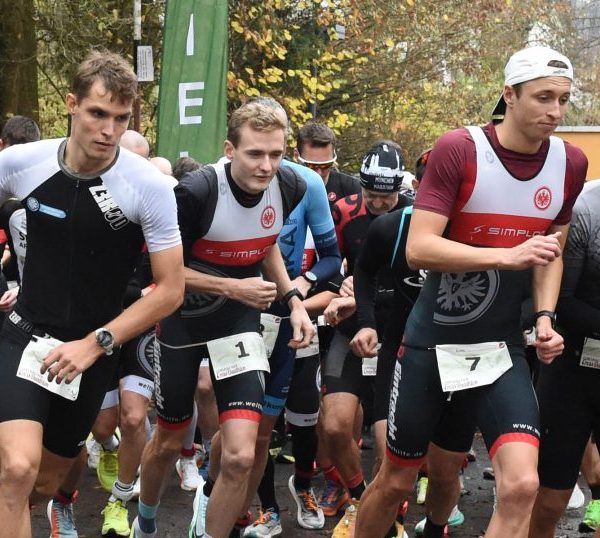 Startphase beim Lorsbacher Cross-Duathlon: zahlreiche Athleten laufen dicht gedrängt los, markiert durch Startbanner und Startfahnen in herbstlicher Waldumgebung.